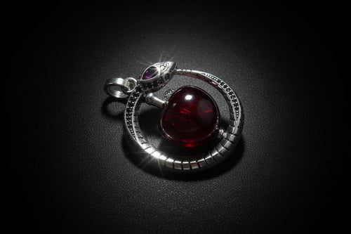 Pendant with red gemstone and silver accents on a white background