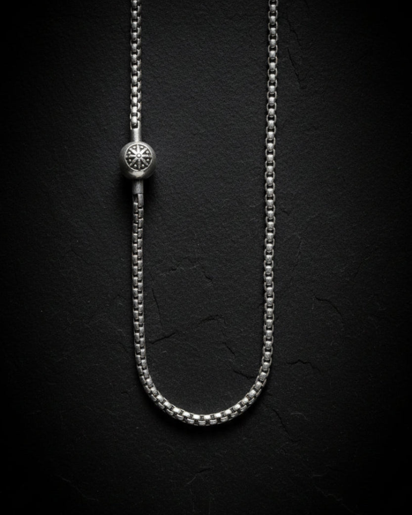 Silver chain necklace on a black textured background