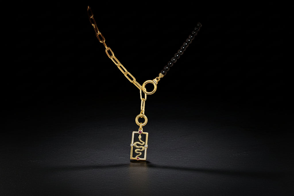 Gold necklace with a black pendant worn by a person on a white background