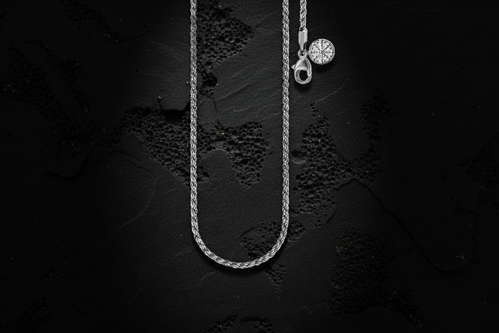 Silver necklace with a pendant on a textured black background