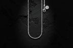 Silver necklace with a pendant on a textured black background