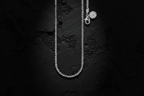 Silver necklace with a pendant on a textured black background